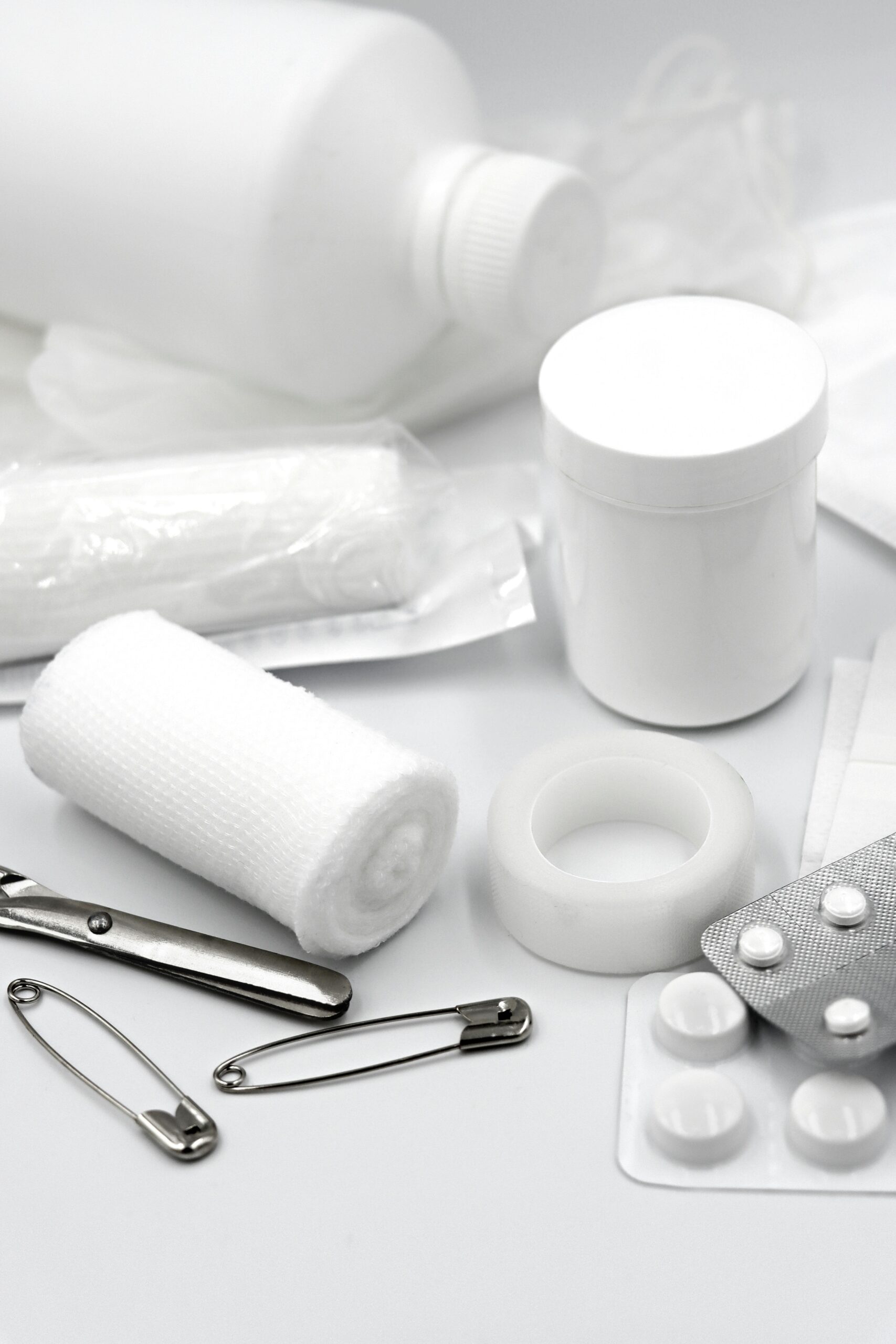 A detailed arrangement of essential first aid supplies including bandages, safety pins, and medication.